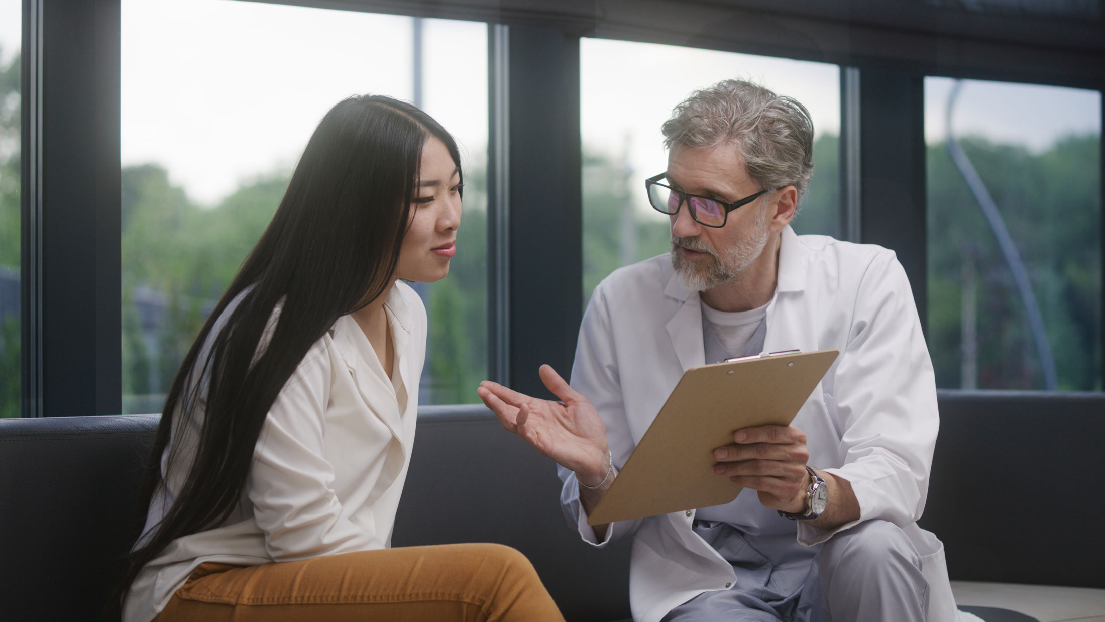 A woman sits on an exam table and talks to a nurse