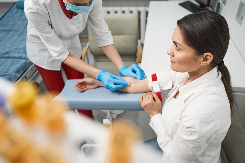 A woman sits on an exam table and talks to a nurse