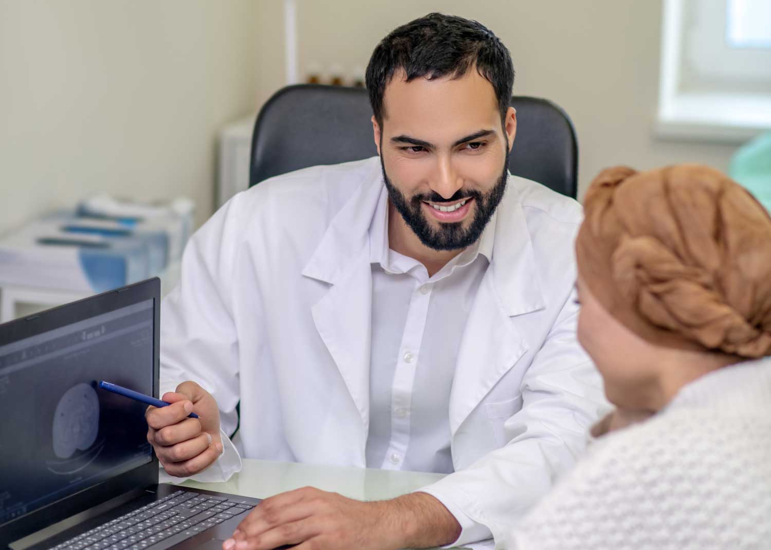 A woman sits on an exam table and talks to a nurse